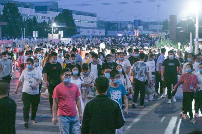 Thousands of workers leave the Foxconn plant  in Zhengzhou city at the end of their shift